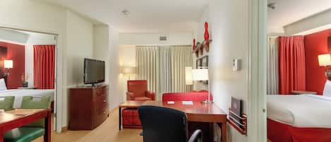 Une chambre d’hôtel avec un lit, un bureau, une chaise, une télévision et un rideau rouge.