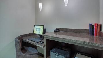 Een werkplek met een computer, printer en boeken op een bureau.