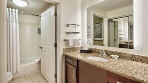 A bathroom with a shower, toilet, sink, and mirror.