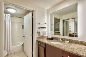 A bathroom with a shower, toilet, sink, and mirror.