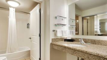 A bathroom with a shower, toilet, sink, and a mirror.