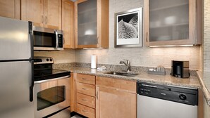 A modern kitchen with stainless steel appliances, wooden cabinets, a granite countertop, and a dishwasher.