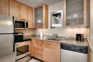 A modern kitchen with stainless steel appliances, wooden cabinets, a granite countertop, and a dishwasher.