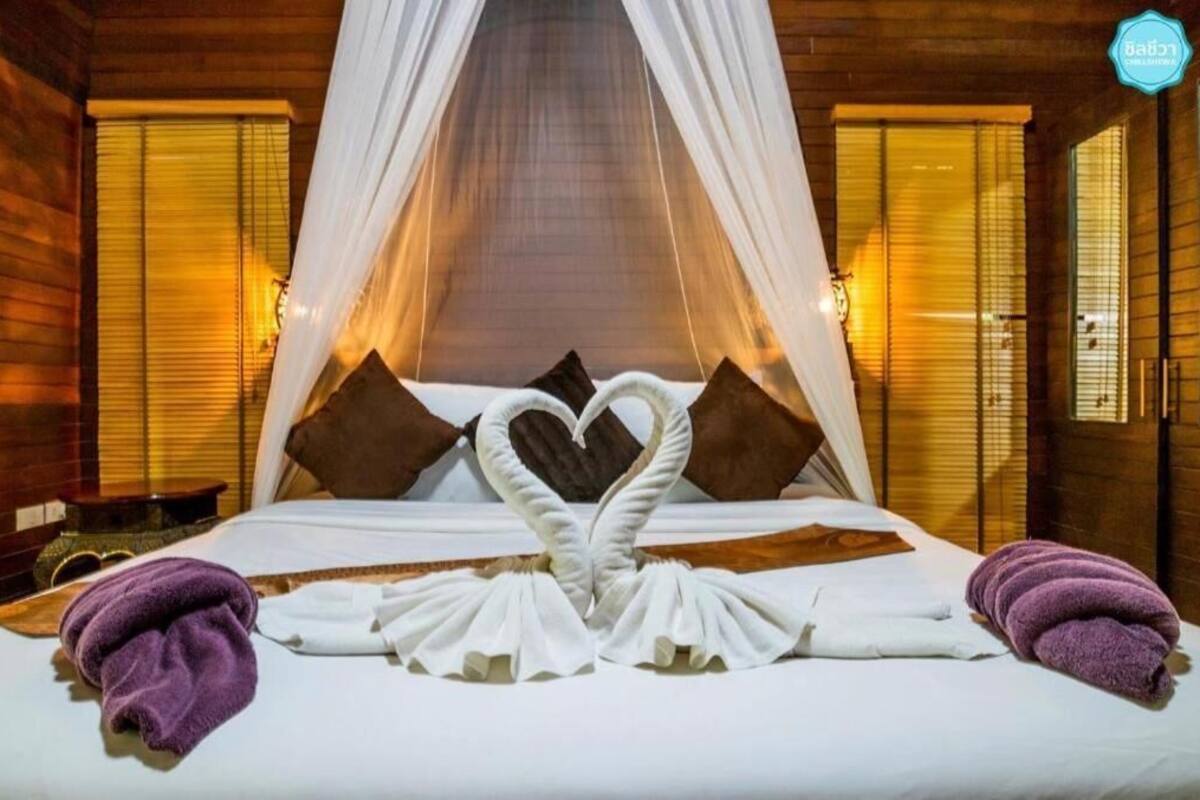 Een bed met een hemelbed, kussens en handdoeken gerangschikt in de vorm van een hart.