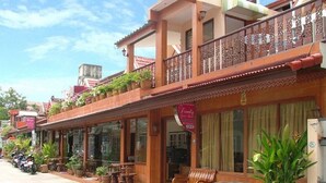 A two-story building with a balcony, potted plants, and outdoor seating. - The Siam Guest House (Pattaya)
