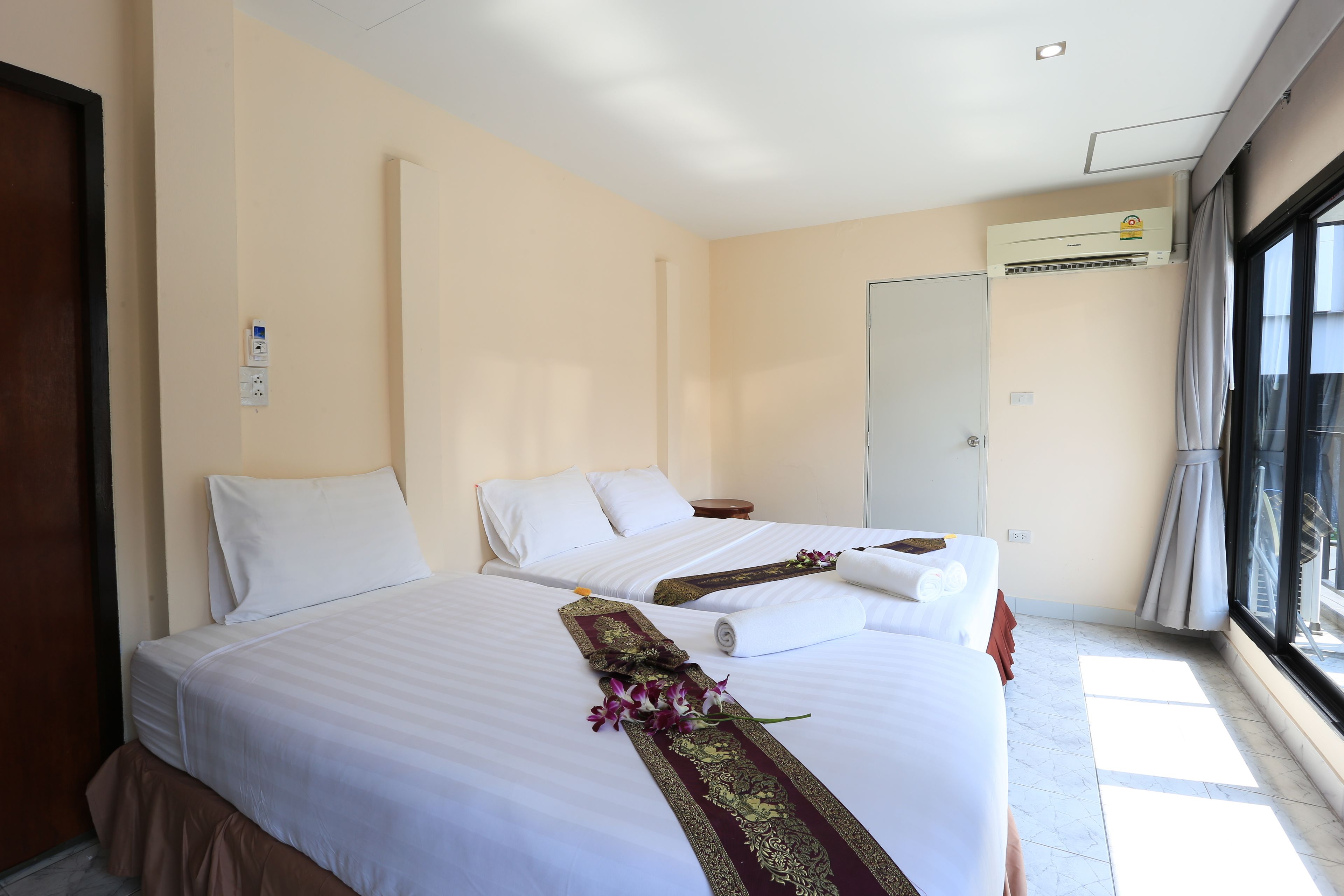 A hotel room with two beds, a large window, and an air conditioning unit.