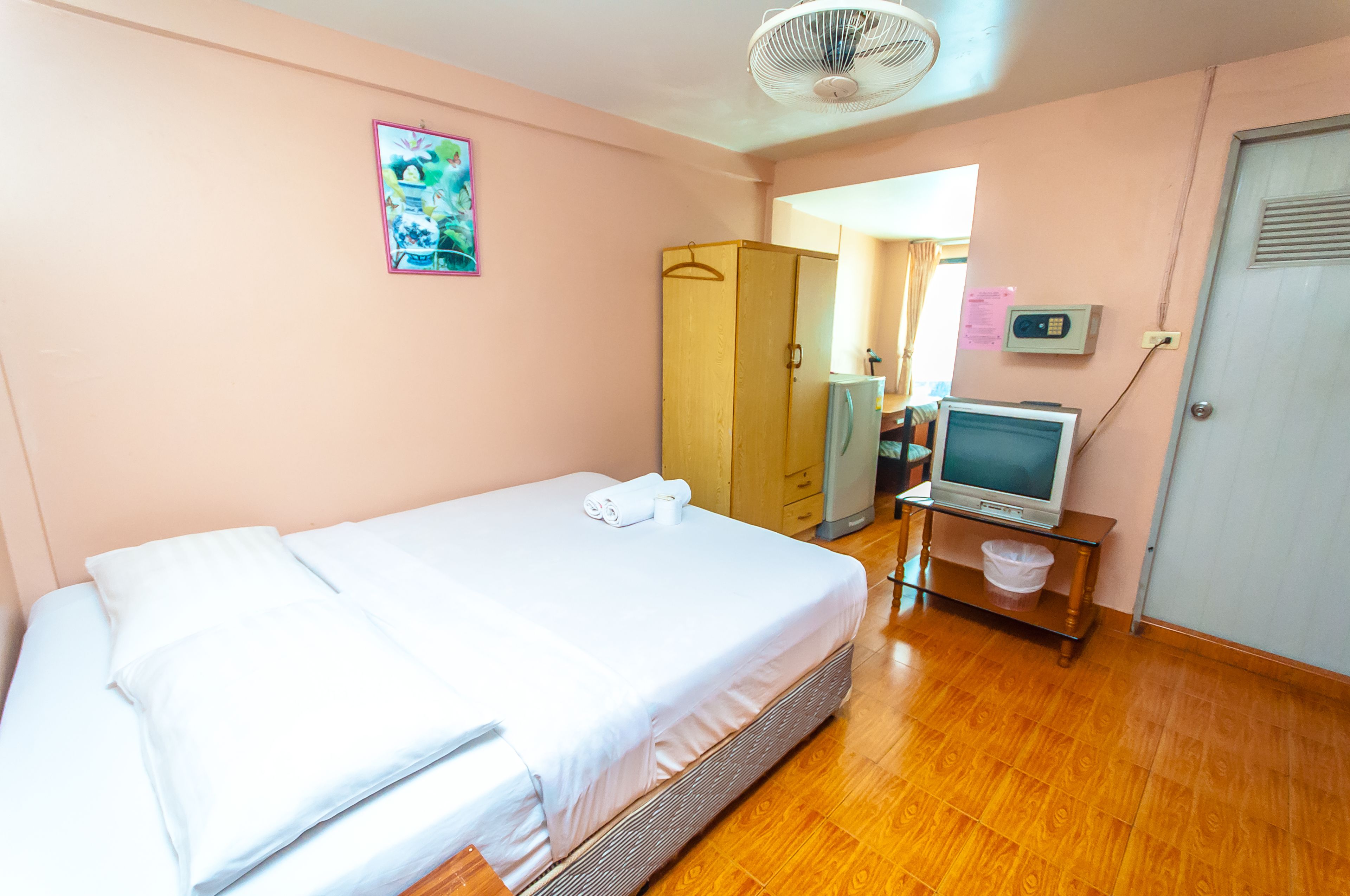 A room with a bed, a TV on a stand, a wardrobe, and a door.