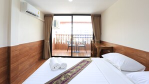 A hotel room with a bed, a desk, and a balcony with a table and chairs. - The Siam Guest House (Pattaya)