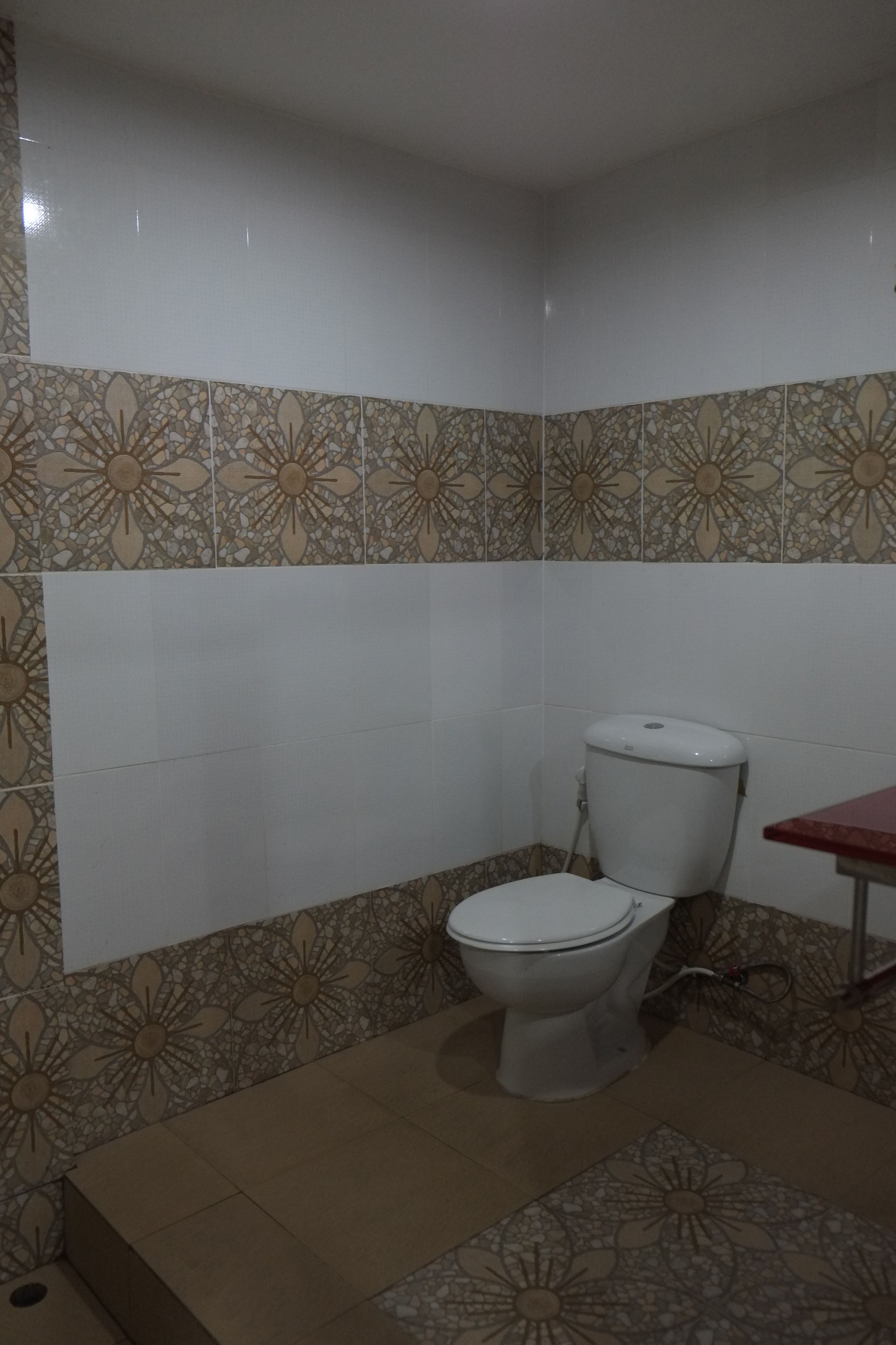 A bathroom with a toilet, a sink, and patterned tiles on the walls and floor.