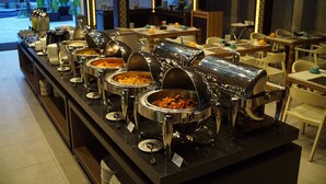 A buffet setup with multiple food stations, including a variety of dishes in metal containers, arranged on a counter. - Grand Barong Resort (Kuta)