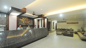 A reception area with a patterned reception desk, a ceiling fan, and a seating area with sofas and a coffee table. - Grand Barong Resort (Kuta)