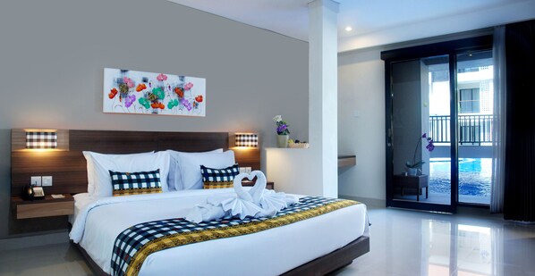 Une chambre d’hôtel moderne avec un grand lit, un tableau au mur, une table de chevet avec un téléphone et une vue sur la piscine à travers la porte vitrée.