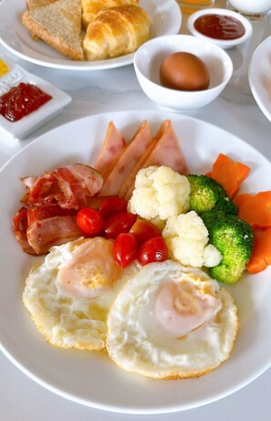 A breakfast plate with eggs, bacon, ham, tomatoes, cauliflower, broccoli, and carrots. - Miloft Sathorn hotel (Bangkok)