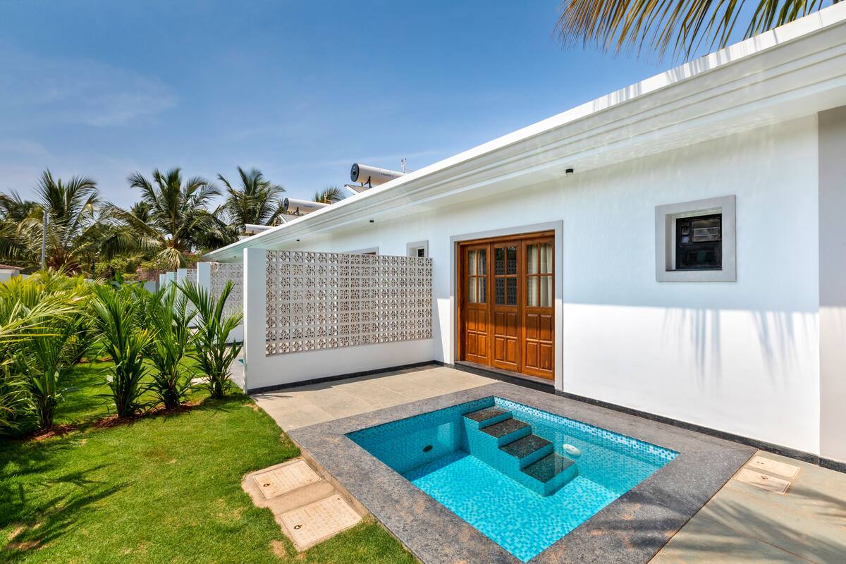 Ein modernes Haus mit Schwimmbad, Holztür und weißer Fassade.