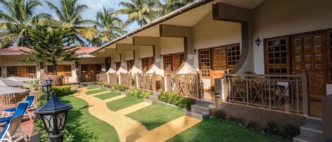A hotel with a courtyard featuring palm trees, a pathway, and outdoor seating.