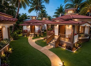 A property with multiple villas, each featuring a tiled roof, a front porch, and a staircase leading to the entrance. - Leoney Resort (Vagator)