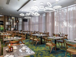 A modern dining area with round tables, wooden chairs, and a patterned carpet.