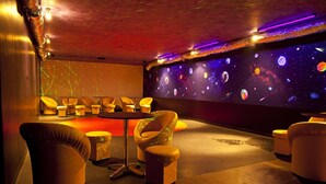 A room with a space-themed wall mural, comfortable seating, and a small table. - Hotel Horyzont (Rzeszów)