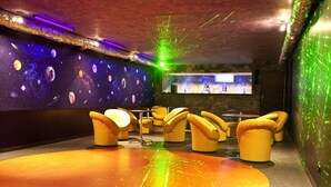 A room with a space-themed wall, yellow seating, and a bar area. - Hotel Horyzont (Rzeszów)
