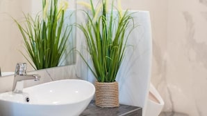 A bathroom with a white sink, a mirror, and two potted plants. - Hotel Horyzont (Rzeszów)