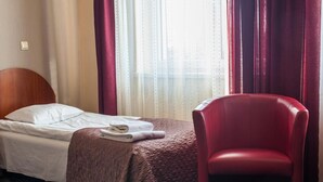 A hotel room with a bed, a red chair, and a window with curtains. - Hotel Horyzont (Rzeszów)