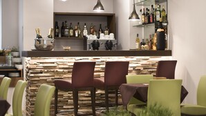 Un espace bar doté d’un comptoir en pierre, de plusieurs tabourets et d’une variété de bouteilles d’alcool.