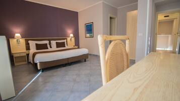 A hotel room with a bed, bedside tables, a chair, and a view of the hallway.