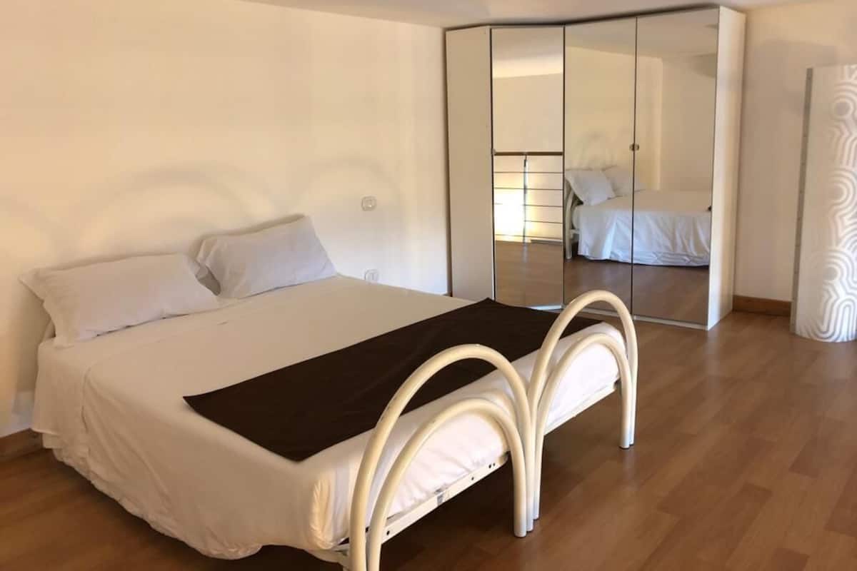 Een slaapkamer met een bed, een spiegel en een kledingkast.