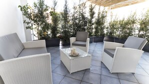 Une terrasse dotée de meubles en osier, notamment des canapés et des fauteuils, disposés autour d’une table basse centrale.