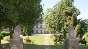A pathway leading to a building surrounded by trees and greenery. - Villa Bregana (Carnago)
