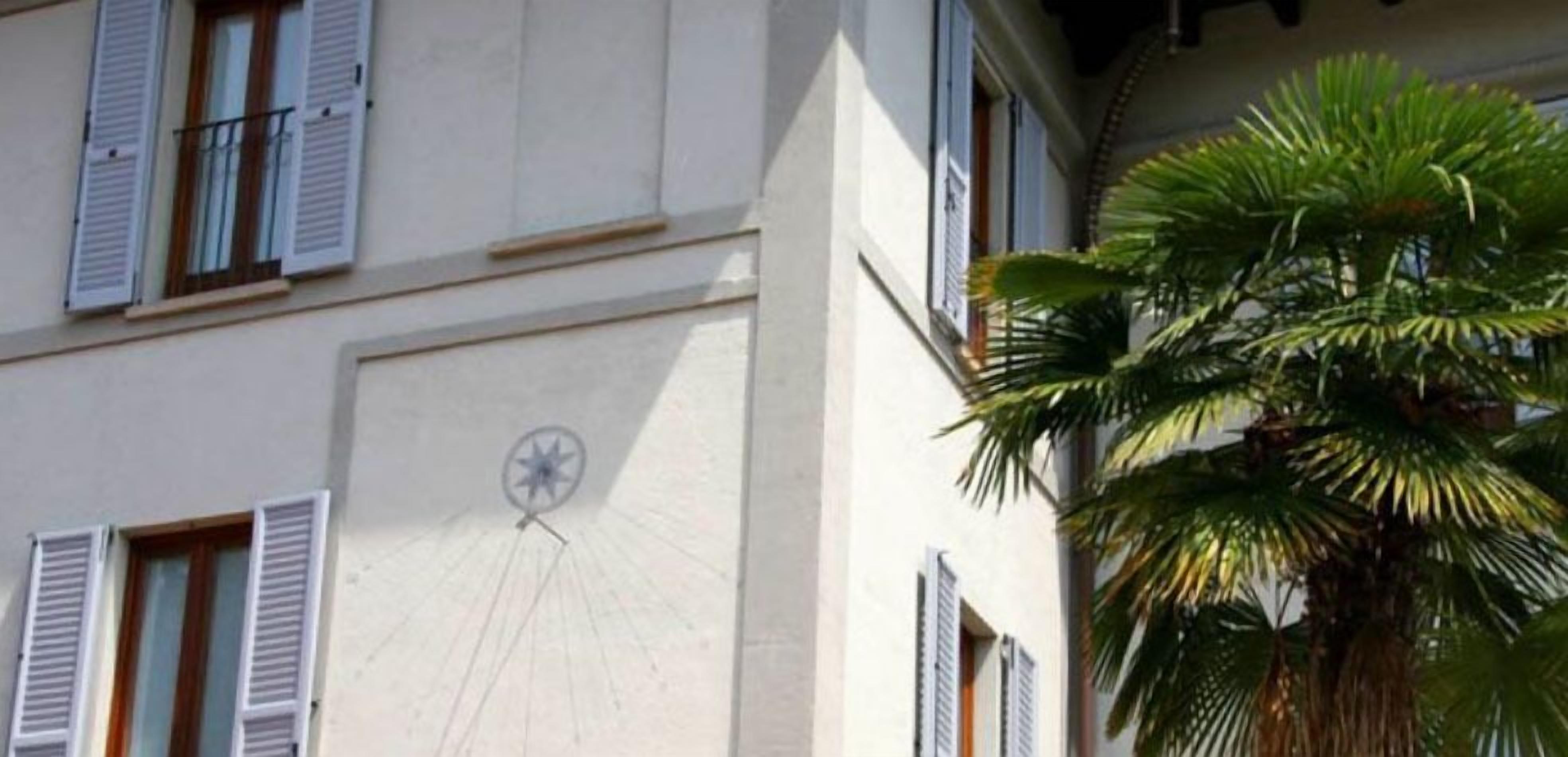 A building facade with multiple windows, shutters, and a clock.