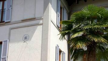 A building facade with multiple windows, shutters, and a clock.
