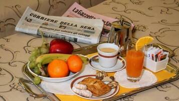 Ein Tablett mit einer Zeitung, einer Obstschale, einer Kaffeetasse, einem Glas Orangensaft und einem kleinen Teller mit Gebäck.