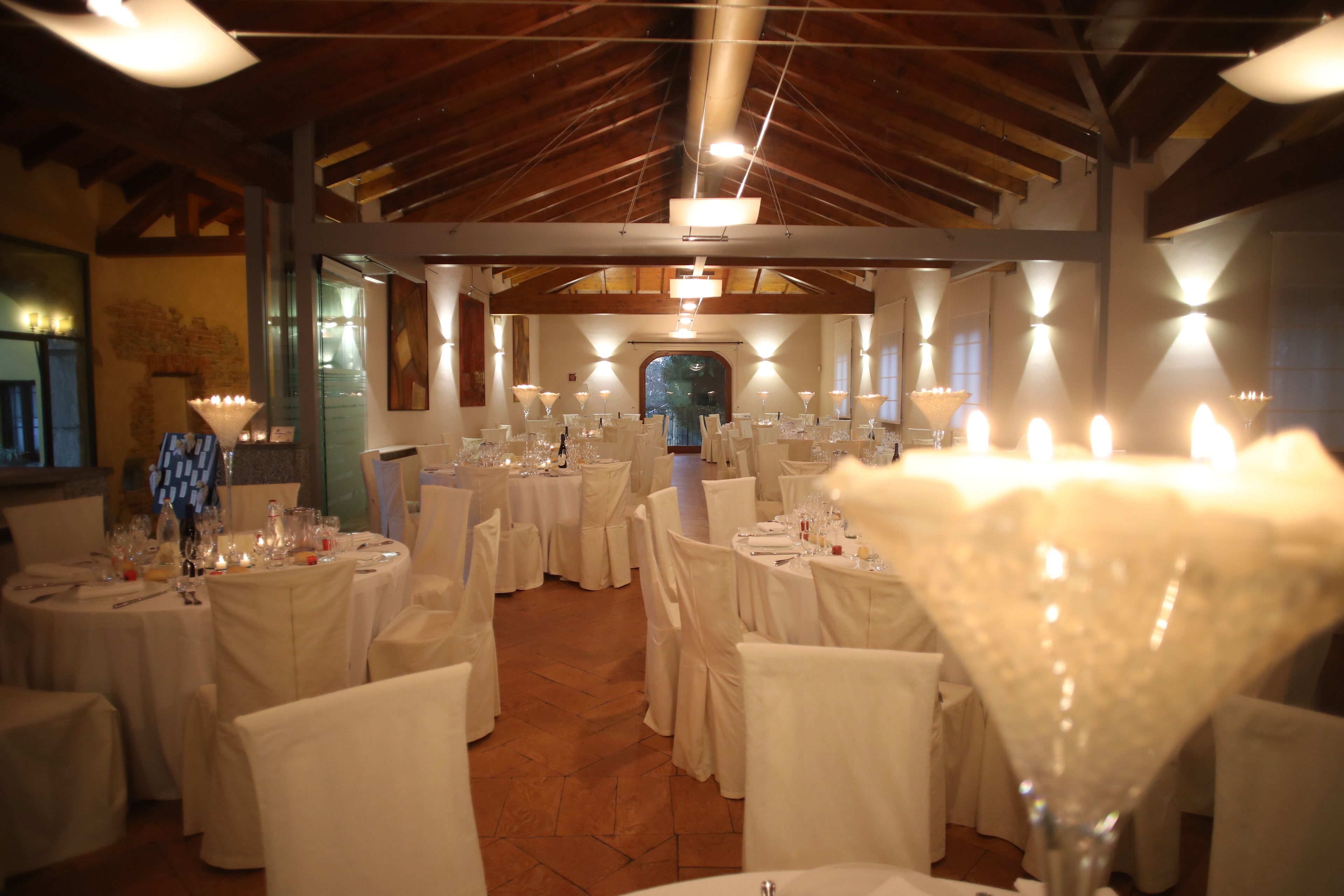 Une salle de banquet avec des tables rondes dressées pour un événement formel, agrémentée de nappes et de chaises blanches.