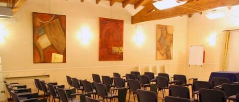 A conference room with rows of chairs, a whiteboard, and abstract paintings on the walls.