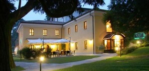 Un hotel con patio, mobiliario exterior y una entrada bien iluminada.