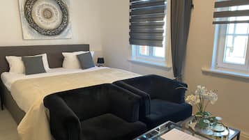 Ein Schlafzimmer mit einem Bett, zwei schwarzen Sesseln, einem Glastisch und einem Wanddekor.
