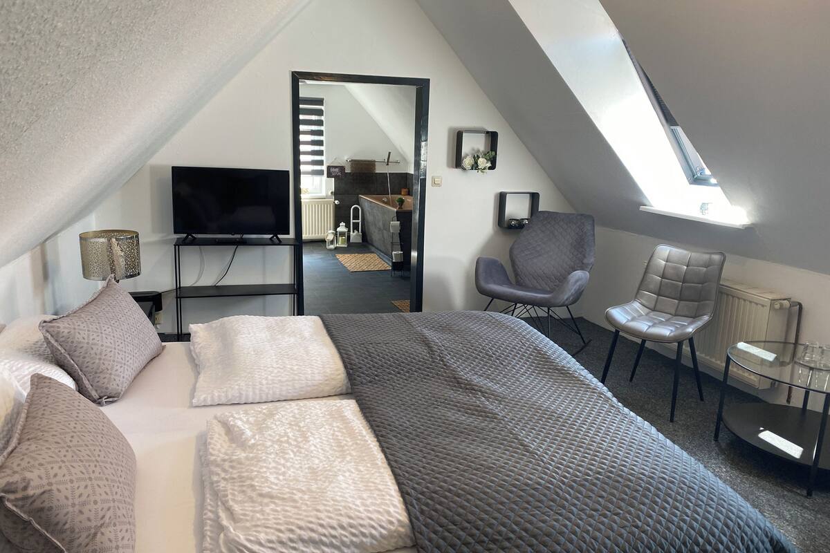 Une chambre de style loft moderne, dotée d’un grand lit, d’un bureau, d’une chaise et d’un téléviseur.