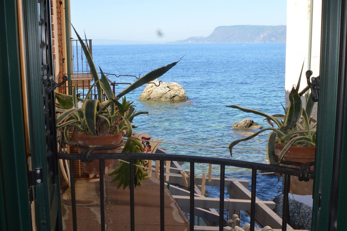 Een balkon met plantenbakken met uitzicht op de kust.