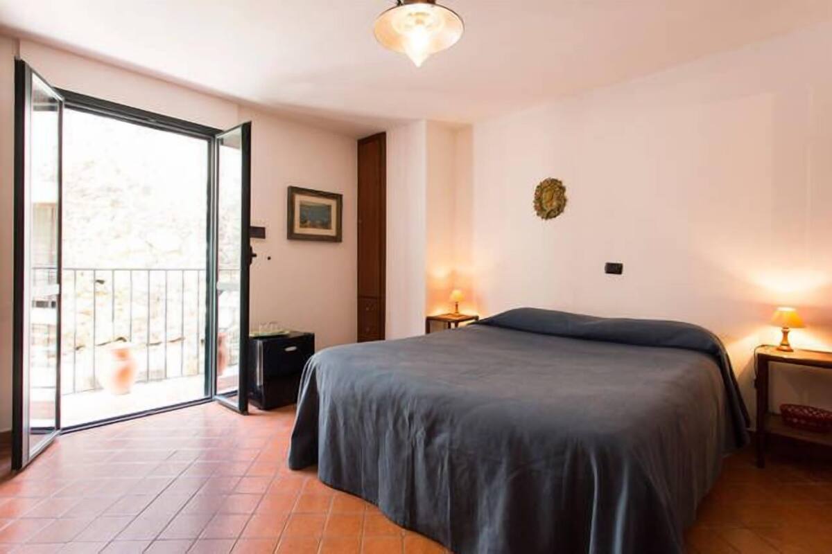 Een slaapkamer met een groot bed, een schuifdeur naar een balkon en twee bedlampen.