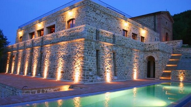 Un bâtiment en pierre avec une piscine devant.