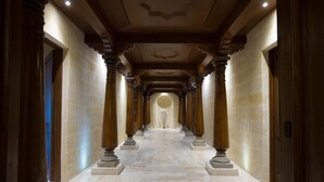 Un couloir de marbre orné de colonnes et d’un chandelier.