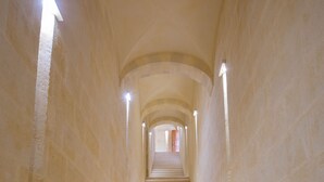 Un long escalier étroit, composé d’une série de marches menant vers le haut, flanqué de murs recouverts d’un revêtement en pierre de couleur claire.