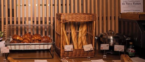 Eine Bäckerauslage mit Brot und Gebäck, ein Korbwägelchen und ein Schild, das den Standort der Bäckerei angibt.