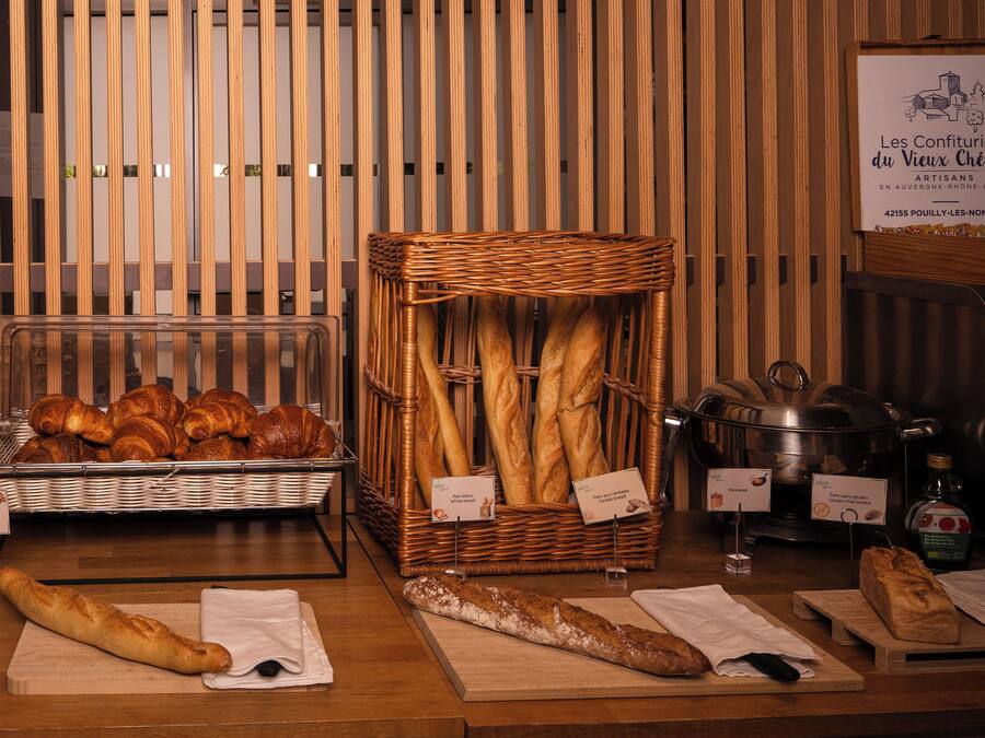 Een bakkerijdisplay met brood en gebak, een rieten mand en een bord dat de locatie van de bakkerij aangeeft.