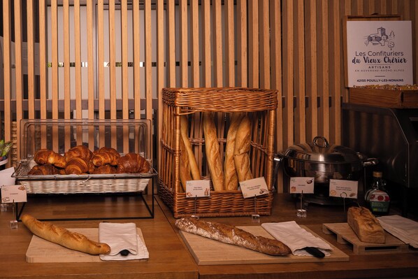 A bakery display with bread and pastries, a wicker basket, and a sign indicating the bakery's location. - Valpré Lyon Hôtel (Ecully)