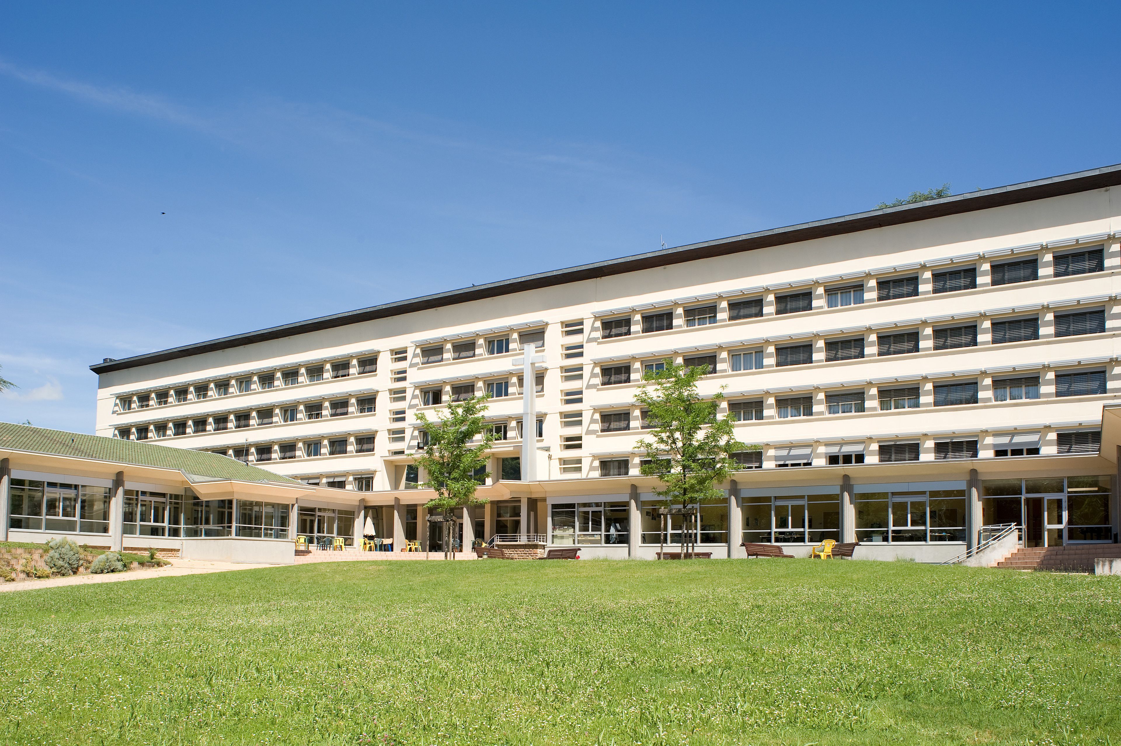A multi-story building with a flat roof, large windows, and a grassy courtyard.