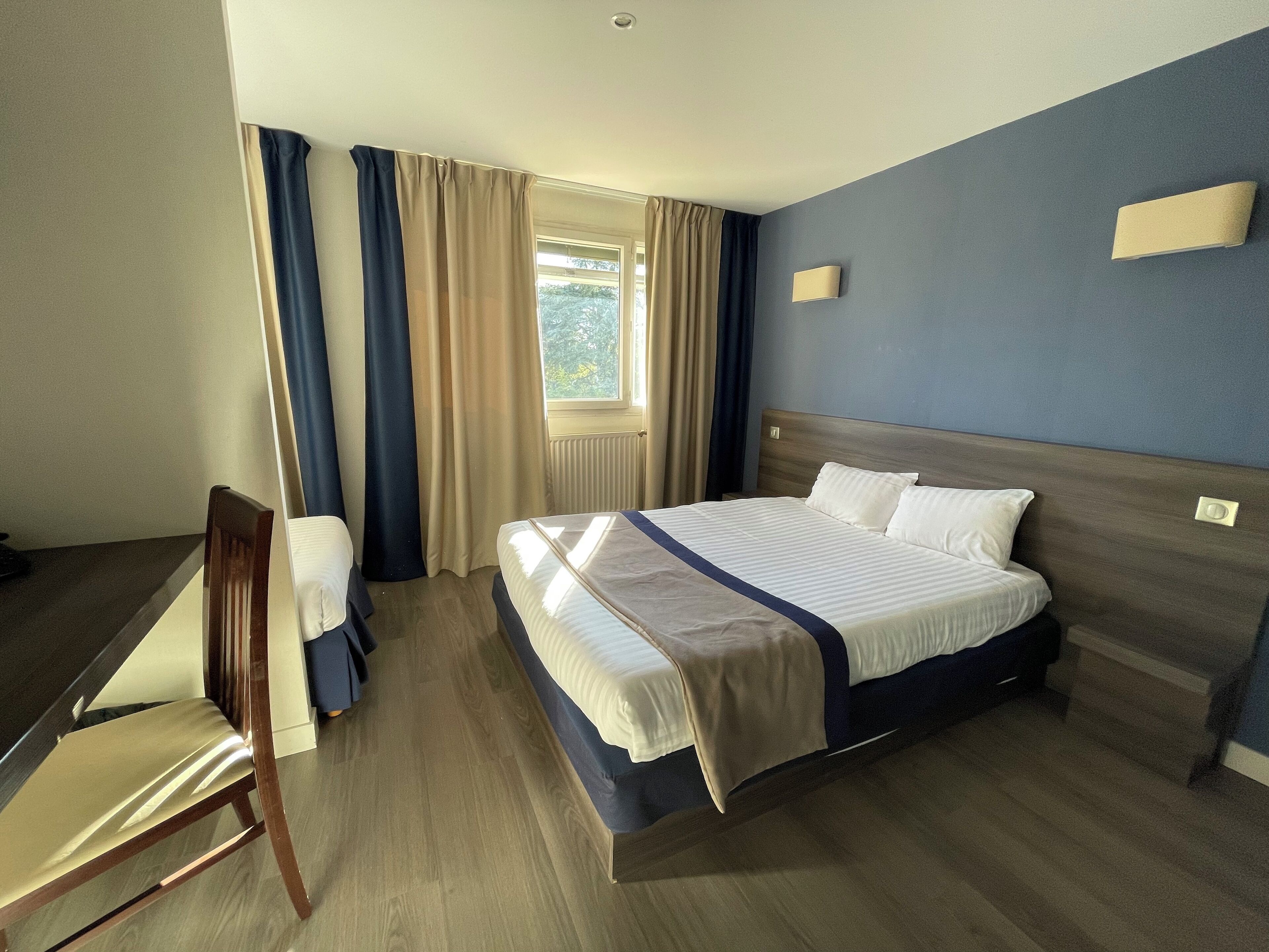 A hotel room with a bed, a desk, and a chair.
