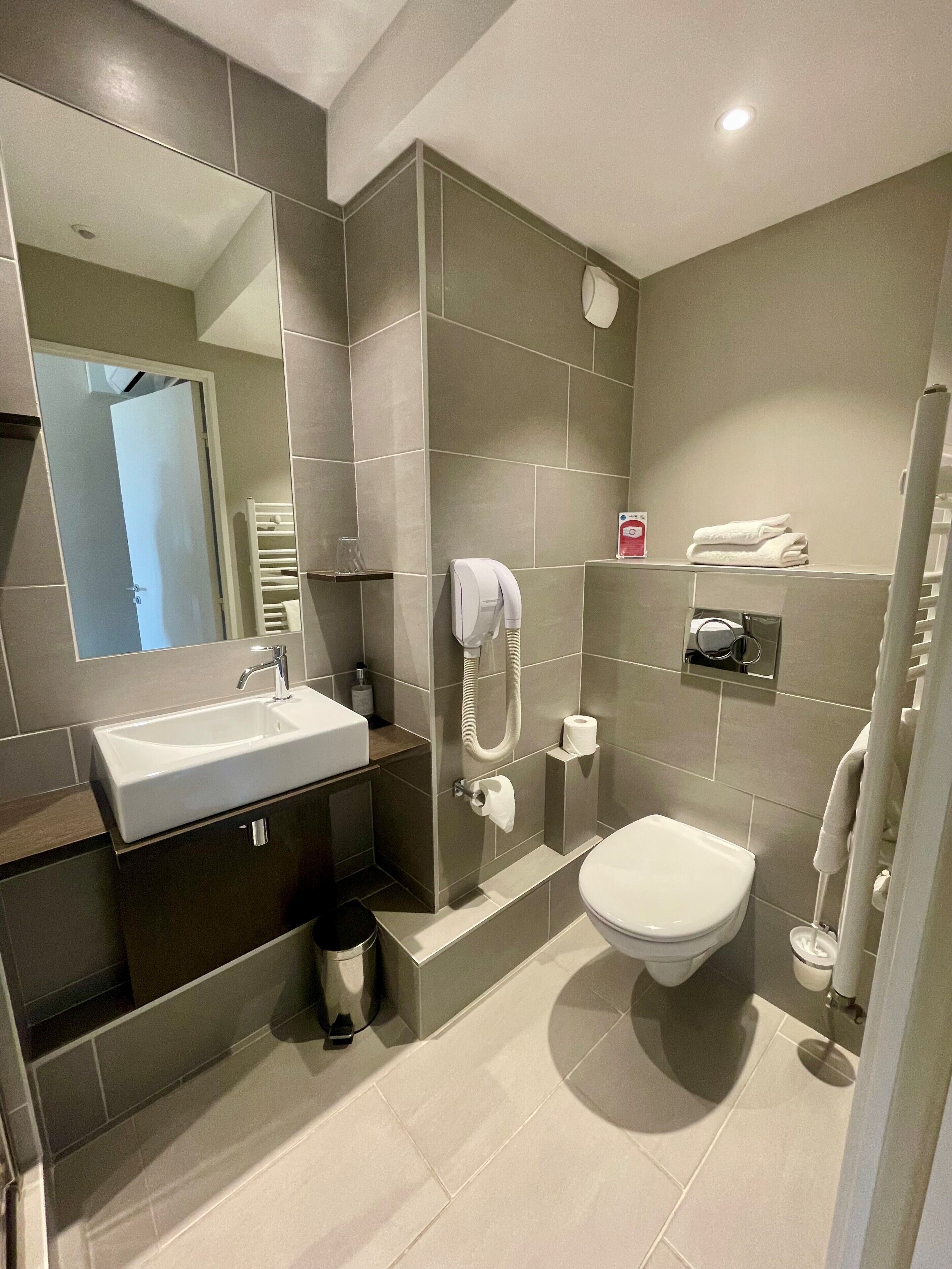 A modern bathroom with a sink, toilet, and shower.