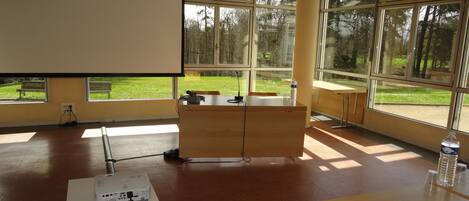 Un aula con un proyector, un pupitre de madera y un banco.
